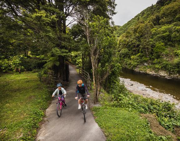 An adult and child cycle along the Hutt River Trail.