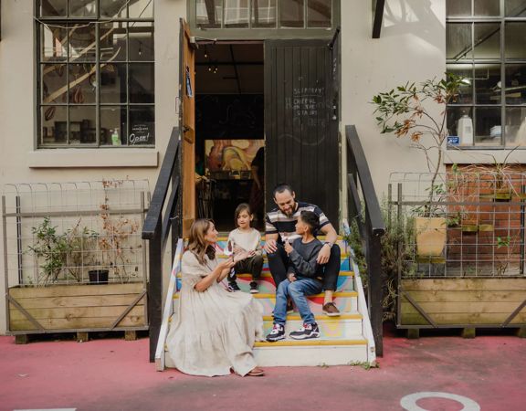 A family of four sits in the colourful steps leading to Wellington Chocolate Factory in Hannahs Laneway.