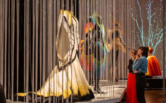 Exhibition visitors at Te Papa looking at previous WOW show garments including one made of feathers