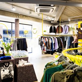 Interior of Good As Gold fashion store in Wellington showing clothing on display on painted yellow clothing racks.