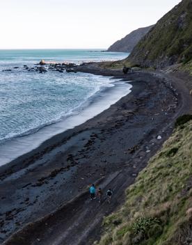 Three people walk along the beach trail at Red Rocks Coastal Walkway.