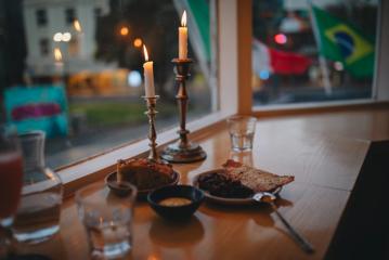 A table by a window with two candlesticks, water glasses and a couple of appetizers at Supra.