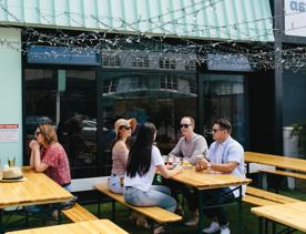 People enjoying drinks at the picnic tables on the patio at Heyday Beer co.