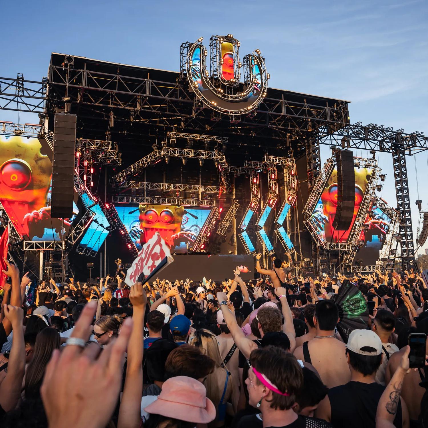 An outdoor stage at Ultra Worldwide Music Festival in Melbourne, Australia, with huge screens, speakers, and a packed cheering audience.