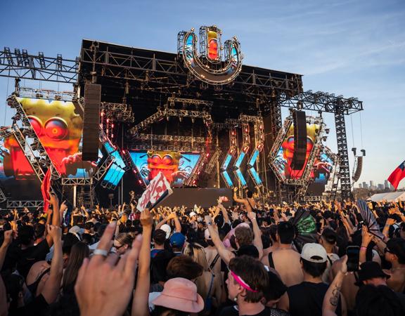 An outdoor stage at Ultra Worldwide Music Festival in Melbourne, Australia, with huge screens, speakers, and a packed cheering audience.