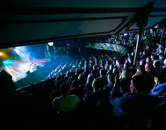 A comedian performs on stage to a packed audience at The Opera House in Wellington.