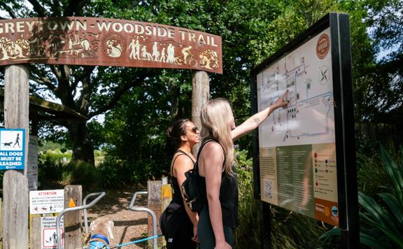 Two people looking at a wayfinding sign on the Greytown to Woodside trail.