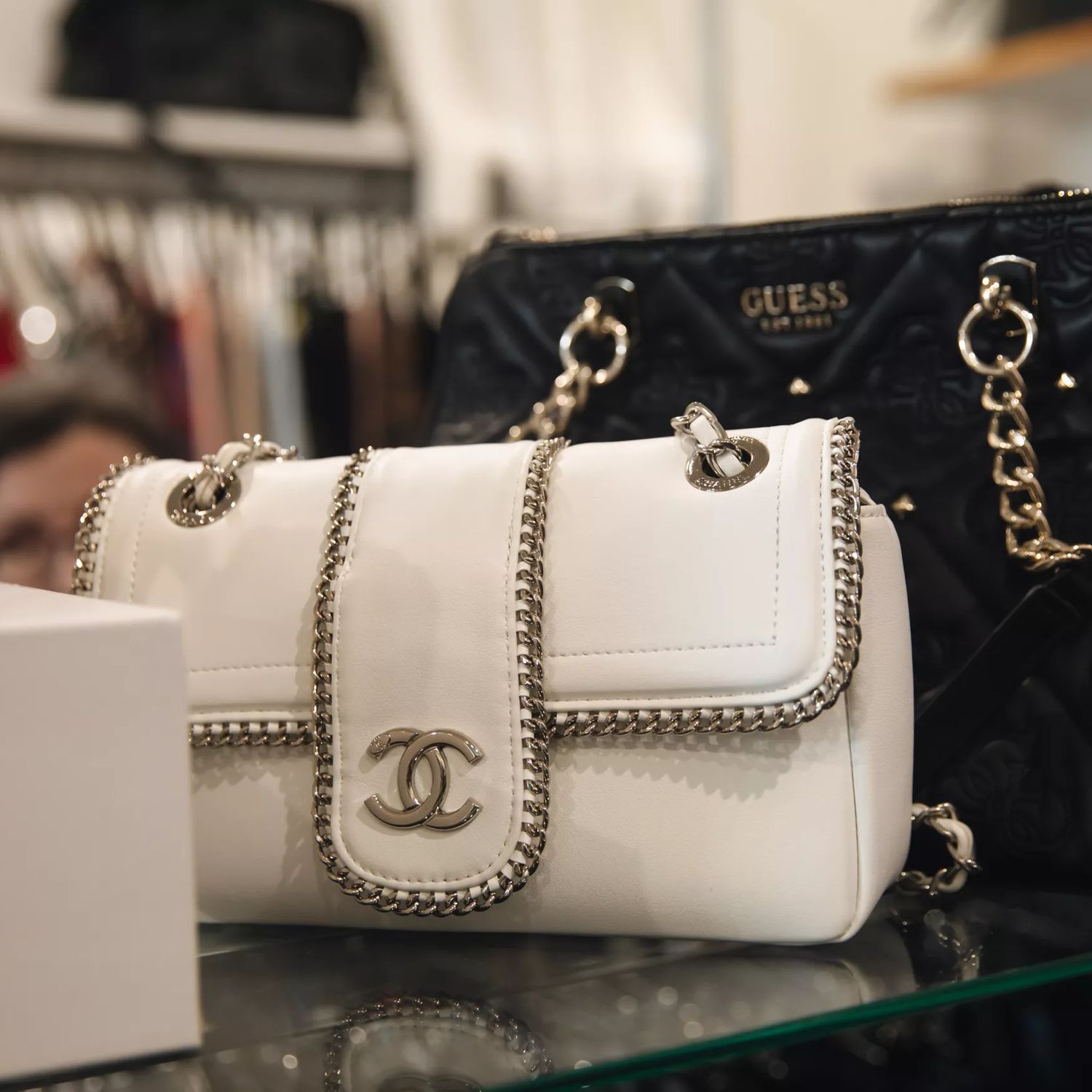 Designer handbags displayed on a glass shelf inside Honour secondhand shop.