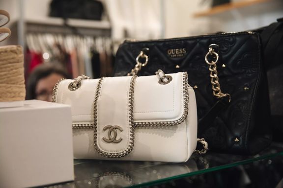 Designer handbags displayed on a glass shelf inside Honour secondhand shop.