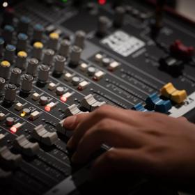 A close up of someone's hand adjusting a sliding dial on a piece of audio equipment.