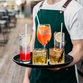 Waiter holding a tray with five colourful cocktails on it.
