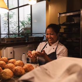 A smiling chef making cheese scones behind the counter at Pravda Café & Grill in Wellington.