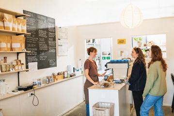 Two people ordering inside The Oatery as a staff member stands behind the counter.