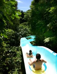 Three kids on a water slide at Wainuiomata Summer Pools.