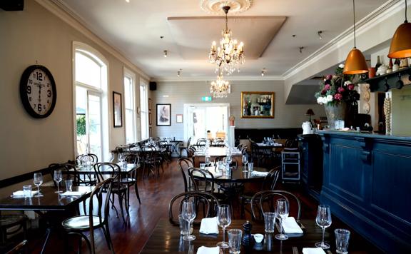 The interior of Union Square Hotel, with dark wooden tables and a dark blue bar.