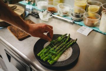 A plate of asparagus is being garnished at Supra.