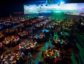Inside the TSB Arena in Wellington, New Zealand during a conference. The lights are dim and the room is filled with people enjoying food and drinks.