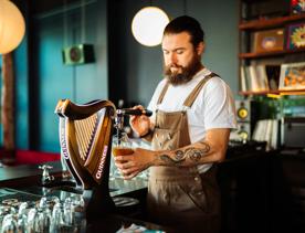 Bartender pouring a glass of Guinness from the tap.