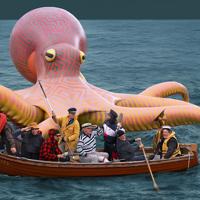 Oversized artificial octopus with people on a boat in front