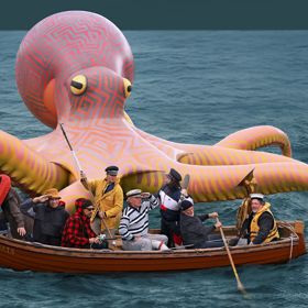 Oversized artificial octopus with people on a boat in front