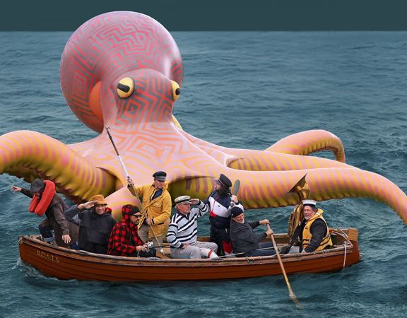 Oversized artificial octopus with people on a boat in front