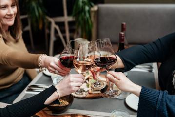 Four people hold out their wine glasses for a toast at The Runholder, a restaurant, tasting room, cellar door, and distillery in Martinborough.