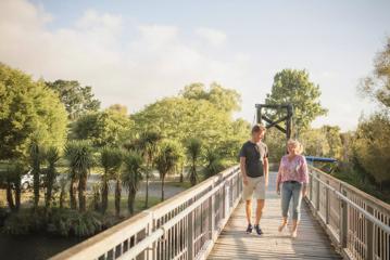 Two people walking along a wooden bridge.