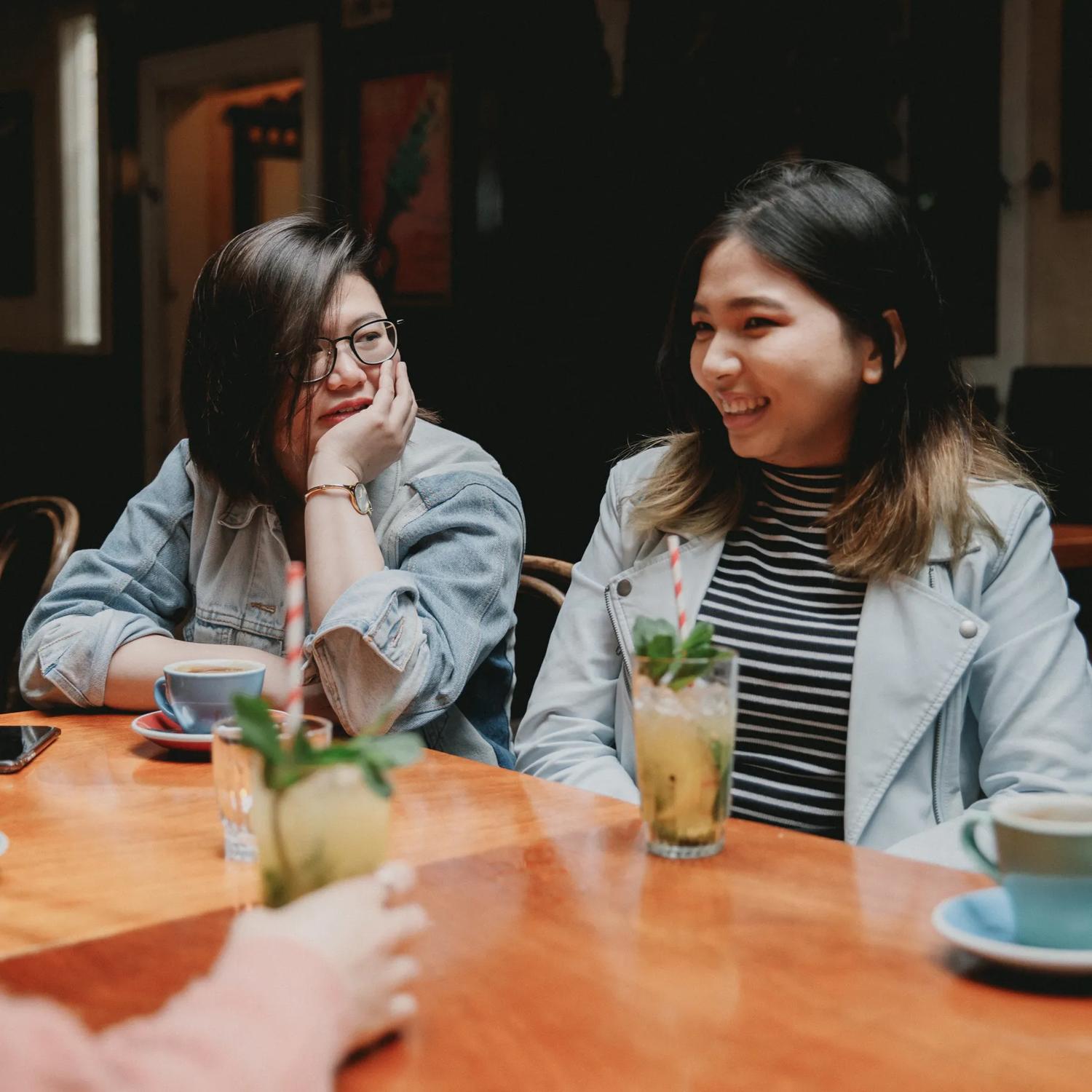 Two friends sitting beside each other enjoy a cappuccino and a mojito at Havana Bar in Te Aro, Wellington.