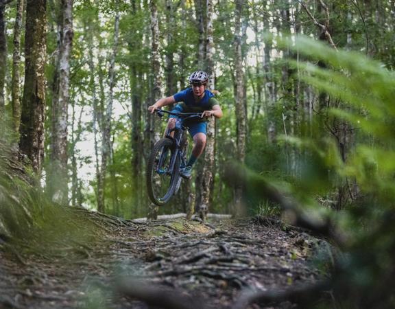 A downhill mountain biker jumps on the Spoonhill trail in Wainuiomata.
