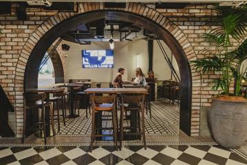 Looking into a brick archway at 4 people sitting on a high table with food.