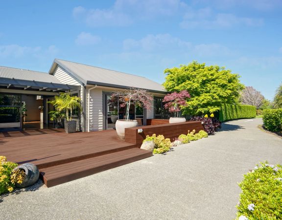 A villa at Parehua Resort is surrounded by a large deck and vibrant trees.
