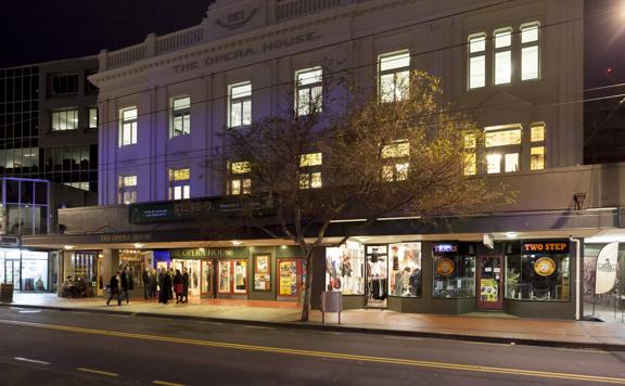 The Opera House in Wellington at night. A small crowd of people are standing in front of the doors.