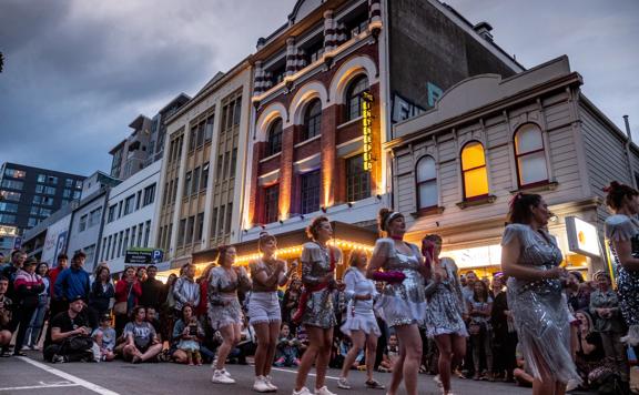 A group of dancers in silver costumes are preforming on the street at CubaDupa.