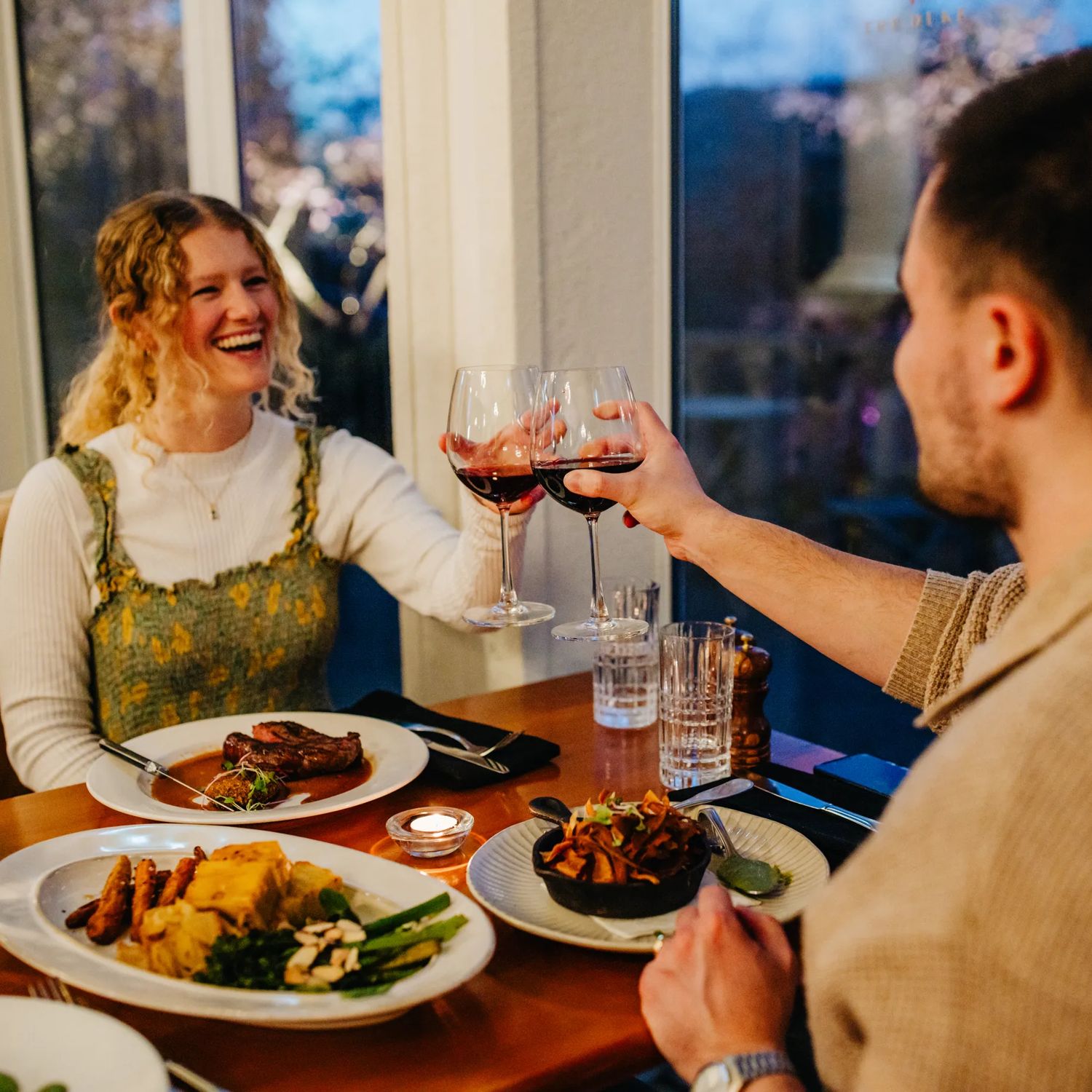 Two people raise glasses of red wine during a fancy dinner at The Duke Restaurant & Bar at Aston Norwood in Upper Hutt.