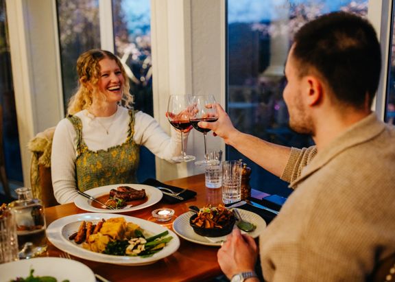 Two people raise glasses of red wine during a fancy dinner at The Duke Restaurant & Bar at Aston Norwood in Upper Hutt.