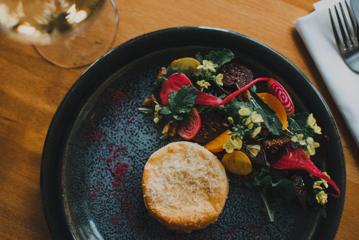 A fine-dining appetizer dish with a cheese pastry and a beetroot salad.