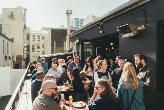 The sunny outdoor patio buzzes with patrons at Garage Project Leeds Street.