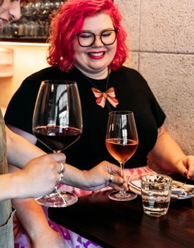 A server delivers two glasses of wine to a table.