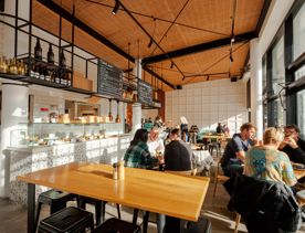Inside Pickle & Pie, a popular café in Te Aro Wellington, is full of people enjoying coffee and food as sunlight floods the space from the glass facade.