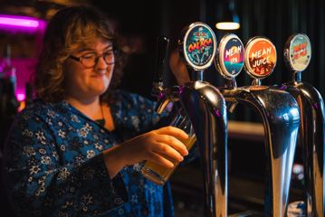 A bartender is pouring a draft beer at Mean Doses, a bar in Te Aro, Wellington.