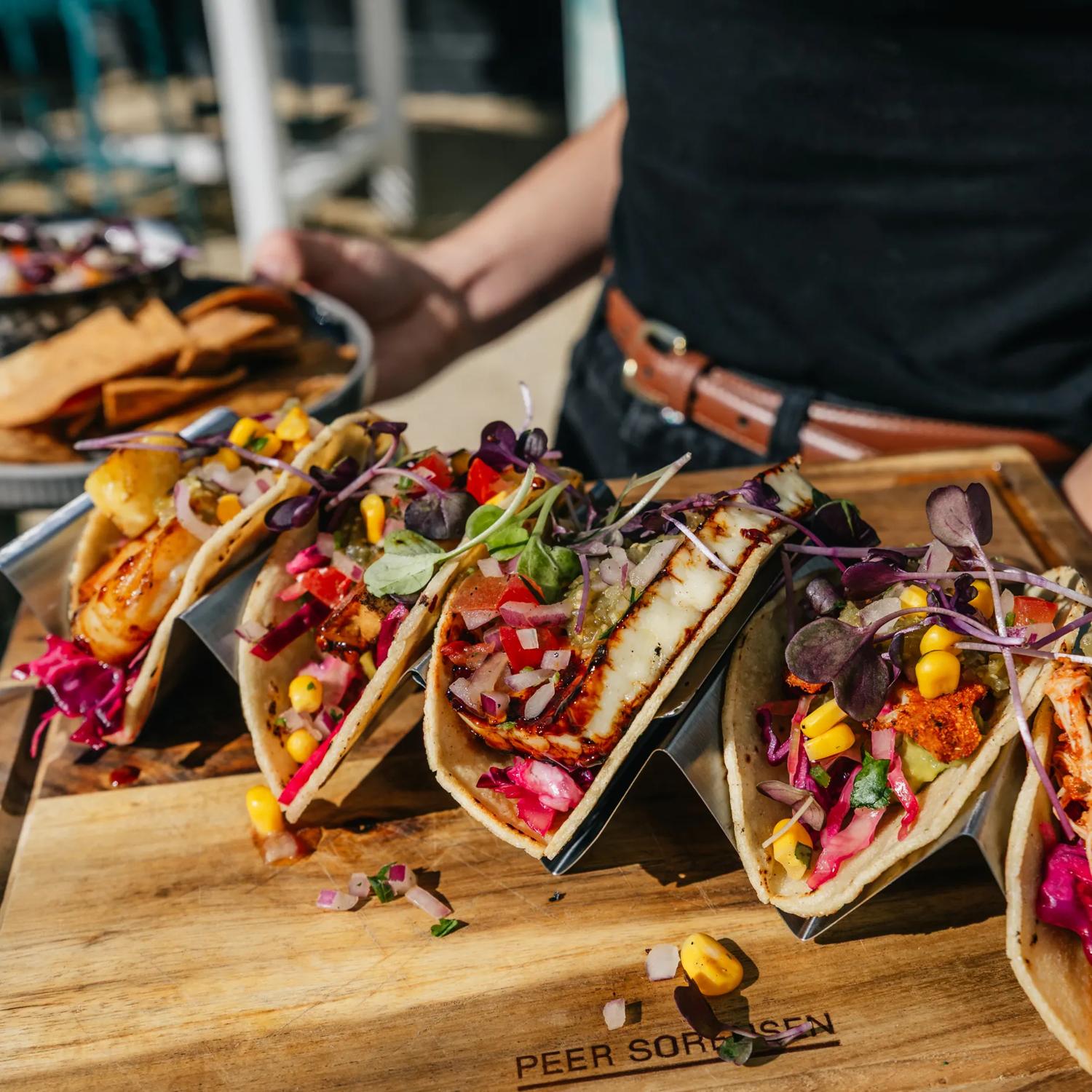 A server carries a taco platter and a ceviche to a table.