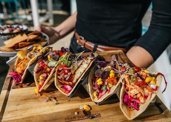 A server carries a taco platter and a ceviche to a table.