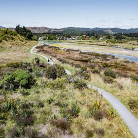 A drone shot of three people walking on the Waikanae Estuary Track.
