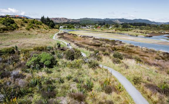 A drone shot of three people walking on the Waikanae Estuary Track.