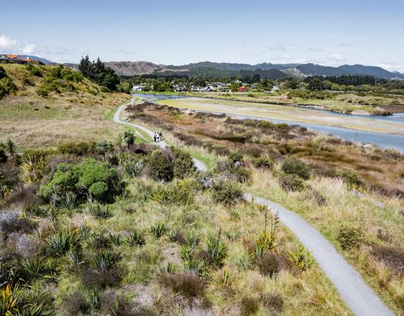 A drone shot of three people walking on the Waikanae Estuary Track.