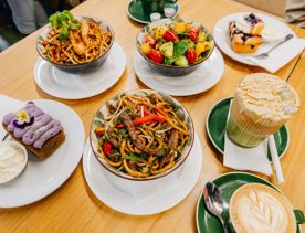 A selection of dishes and coffees on a table at Common Ground Eatery in Johnsonville, including noodles, salad, pastries and latte art.