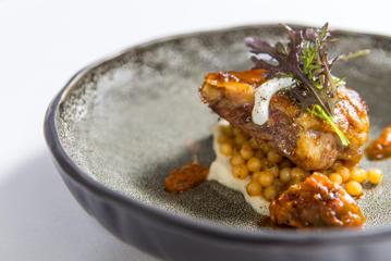 A fine-dining main course dish from Logan Brown restaurant with chickpeas and chicken.