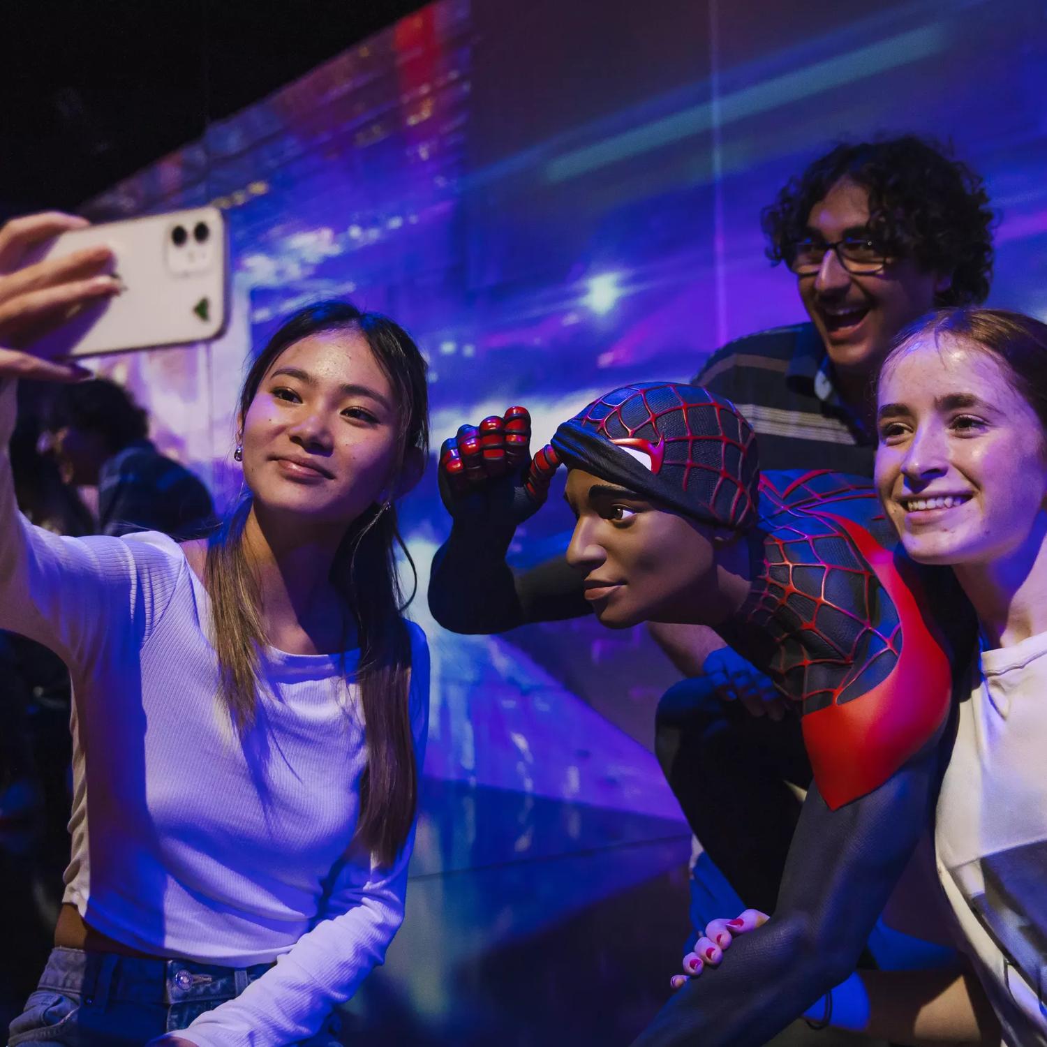 Four teenagers are standing around a statue of Spiderman, taking a selfie at Marvel Earth's Mightiest Exhibition Tākina Wellington Convention & Exhibition Centre.