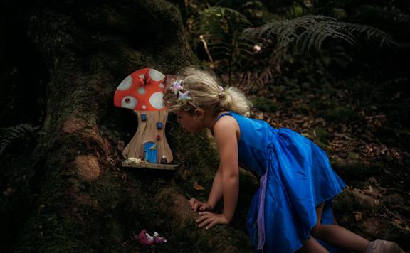 A small child loooking at the fairy forest homes along the Horoeka scenic reserve path.