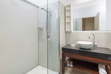 A bathroom at CityLife Hotel has a walk-in white tiled shower and a basin sitting on a black stone countertop.